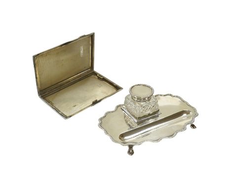 An Edwardian silver shaped oval inkstand, with wavy border, silver mounted glass well and pen recess, Skinner &amp; Co, Londo