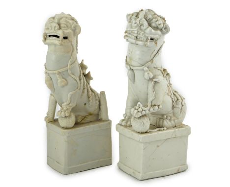 Two large Chinese Dehua blanc de chine Buddhist lion joss-stick holders, Kangxi period, each seated, one paw raised on a ball