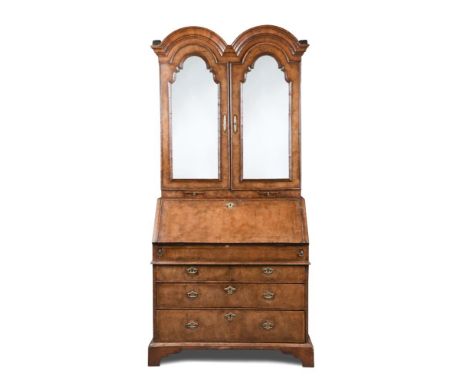 A Queen Anne and later walnut bureau bookcase, with double dome arched top, mirrored doors and candle slides, above a fall en