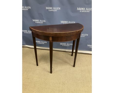 A 19th Century mahogany demi-lune fold over card table, the plain top cross banded and satinwood strung opening to reveal a g