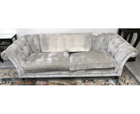 A modern silvered velvet style upholstered buttoned scroll arm sofa on turned mahogany front legs to brass caps and castors i