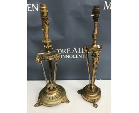 Two gilt brass table lamps in the Empire style, both with ram's head and hoof decoration, one on paw feet, the other on scrol