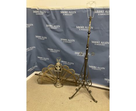 A brass peacock style fire screen with pierced panels, 68 cm high including handle, together with a brass telescopic lamp sta