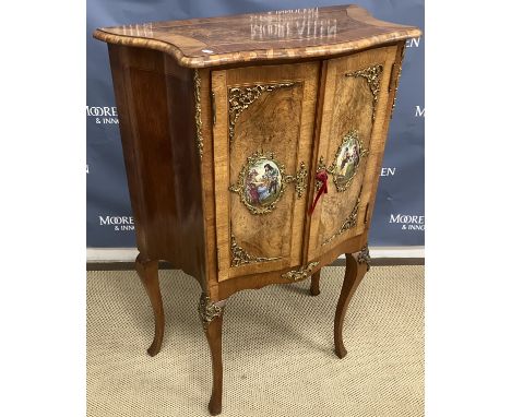 A 20th Century burr walnut side cabinet in the Louis XV taste the serpentine fronted top over two cupboard doors set with sev