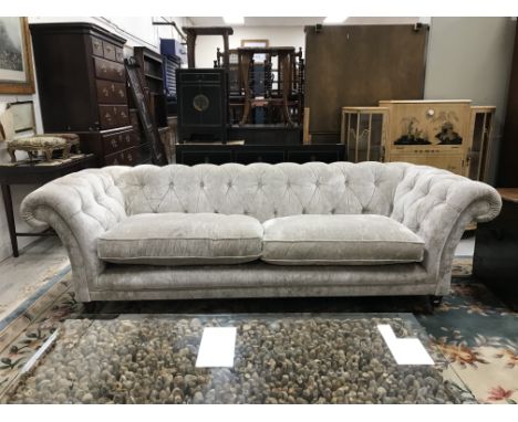 A modern silvered velvet style upholstered buttoned scroll arm sofa on turned mahogany front legs to brass caps and castors i