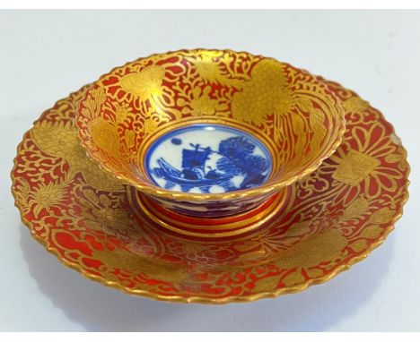 A signed Kutani porcelain cup and saucer in Kinrande palette decorated with golden ho-ho birds against a red ground with cent