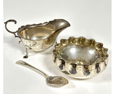 A Sheffield silver George III style sauce boat with scalloped top top and reverse C scroll handle raised on tripod supports a