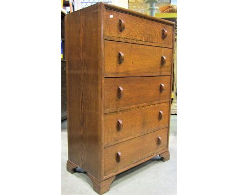 A Herbert Gibbs oak bedroom chest of five long slightly graduated drawers with moulded half ring handles and raised on bracke