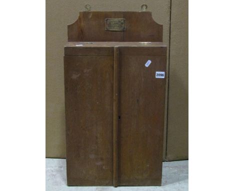 Vintage oak wall mounted chisel cabinet enclosed by two doors, with partially fitted interior with label 'Manufactured by W M