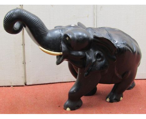A large ebonised timber model of an elephant, its trunk raised, 75cm long 