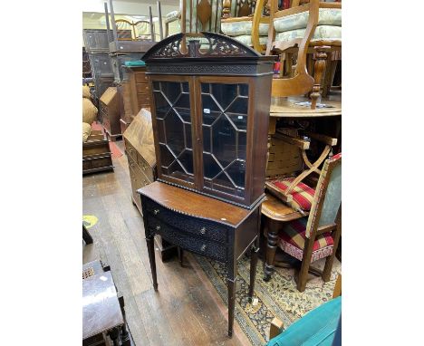 An Edwardian mahogany cabinet, the lower section enclosed by two serpentine drawer with blind fret detail, over an open frame