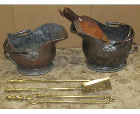 Two 19th century copper helmet shaped coal scuttles with loop handles, a set of three brass fire irons with pierced shovel, a