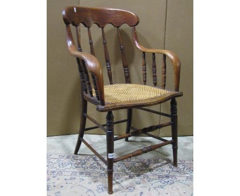 A late Victorian/Edwardian oak, or possibly ashwood, spindleback armchair with cane panelled seat raised on ring turned and t