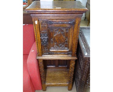 An Antique oak side cabinet of narrow size, with carved and fielded panels and single door, with shelf below, W47cm, H112cm