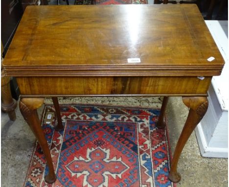 A 1930s cross-banded walnut rectangular fold over card table, on shell carved cabriole legs, W68cm