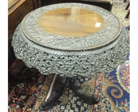 An early 20th Century Burmese carved rosewood occasional table, the centre field within a carved band and foliate decorated p