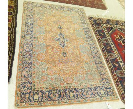 A Persian rug, the central medallion in dark blue, pink, yellow and pale green on an apricot floral decorated ground within b