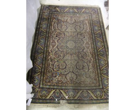A Persian silk rug, the centre medallion in blue and pale brown on a stylised floral decorated ground within blue, green and 