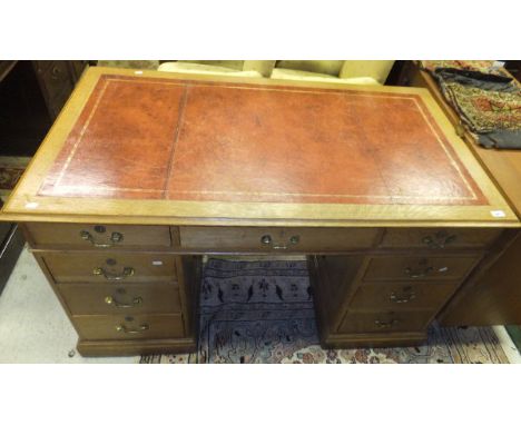 An oak kneehole desk, the tooled and gilded leather insert top above central drawer flanked by two further drawers on two ped