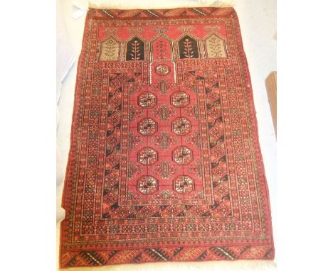 A Turkoman prayer rug, the central panel with repeating elephant foot medallions on a dark red ground, within a red, orange a