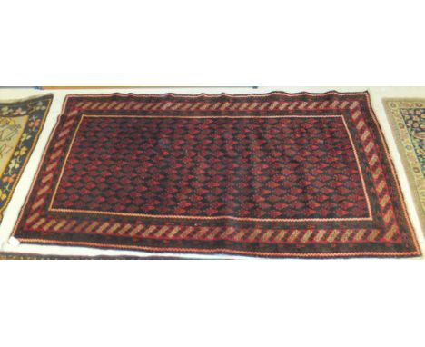 A Caucasian rug with all-over stylised foliate decoration in red on a black ground, within dark red, madder and cream diamond