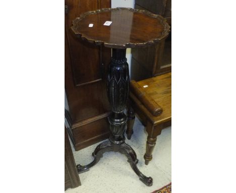 An Edwardian mahogany plant stand, the pie crust edged top on a heavy carved pedestal to hipped cabriole tripod base and scro