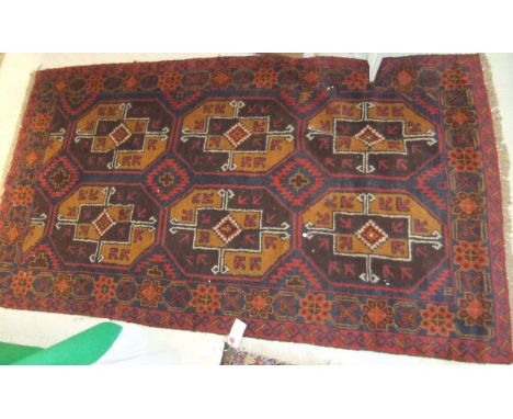 A Bokhara rug, the six central elephant foot medallions in aubergine, mustard, red and cream, within a blue, red, mustard and