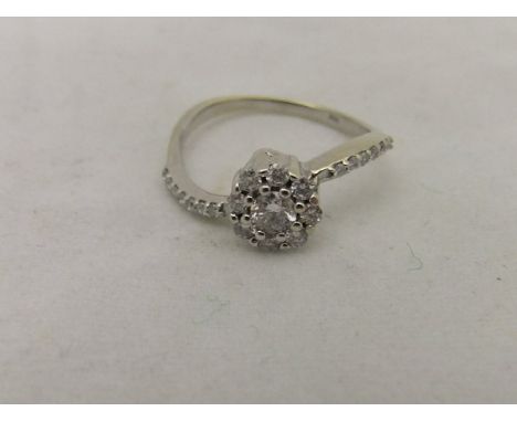 A 14ct white gold diamond set cluster ring with diamond chips to shoulders