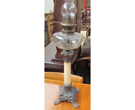 A Victorian oil lamp with a cut glass reservoir on a tapering marble column and cast metal base