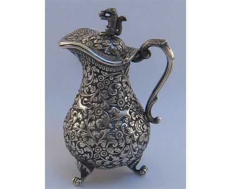 An Indian silver covered cream jug, unmarked, probably Cutch, late 19th century, baluster on three leafy paw feet, profusely 