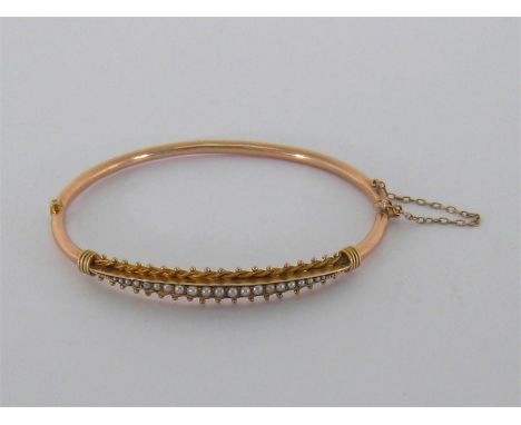 A Victorian gold and seed pearl bangle, set to the front with a panel of graduated seed pearls, to a box snap clasp, inner di