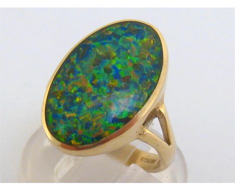 A 9 carat gold and opal doublet ring, the rub over set oval doublet 19.3 x 12mm, to bifurcated shoulders, the shank fully hal