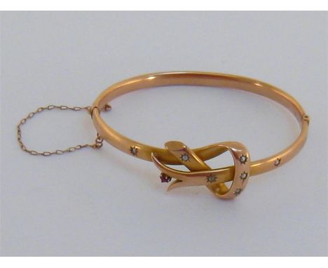 A 19th century gold, ruby and split pearl bangle, the knot motif gypsy set at intervals, with a small ruby accent, 6cm intern