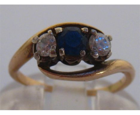 A sapphire and diamond three stone ring, the round cut sapphire 3.2mm between two brilliants within a cross over setting, the