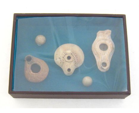 A leatherette covered display box of Roman artefacts comprising three oil lamps and two ceramic marbles.Condition reportGood 