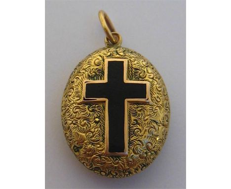 A Victorian gold and black enamel mourning locket, engraved overall with arabesques, a raised black cross to the front, a gla