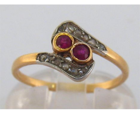 A 14 carat gold, ruby and diamond ring, the two collet set rubies obliquely mounted in a rose cut cross over surround, the sh