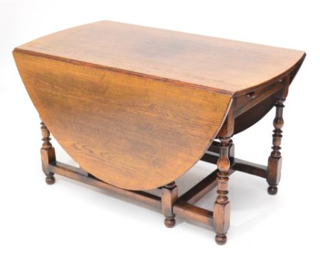 A large reproduction oak drop leaf gateleg dining table raised on baluster ring turned and block supports.