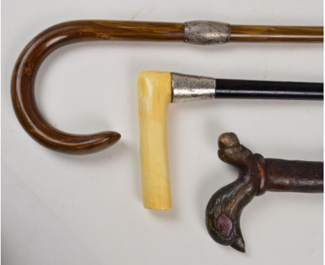 Three walking sticks; an ebonised example with hallmarked silver collar and horn handle, a curved handled example with a hall