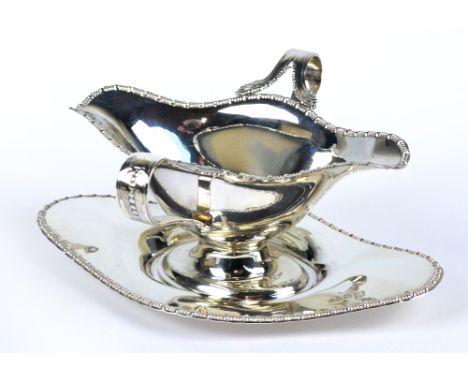 BARKER BROS; a George V hallmarked silver twin lipped saucer boat with two loop handles with cast decorated rim, raised on ov