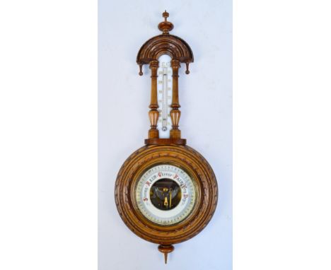 A 20th century carved walnut aneroid barometer with enamel dial, length 57cm.