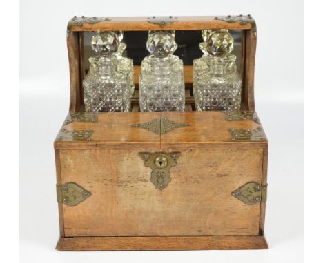 An Edwardian oak and electroplated mounted combination tantalus/smokers' compendium housing three clear hobnail cut glass dec