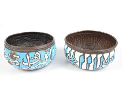 Two similar c.1900 Islamic copper and enamel circular bowls embossed and painted in blue and white enamel with a band of call