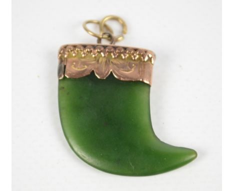 A 9ct yellow gold mounted spinach green jade pendant modelled as a tiger's tooth, height 2.5cm excluding suspension ring.