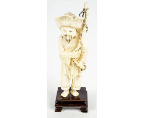 A Japanese Meiji period ivory okimono of a man holding agricultural tools, height 15.5cm excluding hard wooden base on bracke