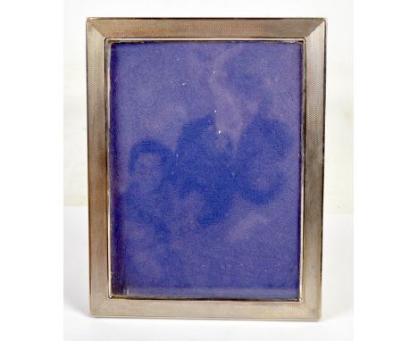 A silver plated rectangular frame with overall engine turned decoration, aperture 23.5 x 17.5 cm, with easel back.