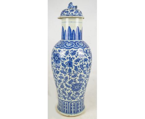 A large 19th century Chinese vase and cover painted in underglaze blue with floral motifs on foliate scroll ground within two