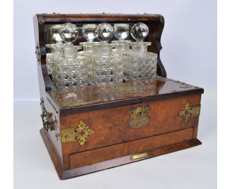 A Victorian figured walnut tantalus/smoking compendium, the raised top section above three hobnail cut glass decanters with l