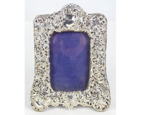 A Victorian hallmarked silver fronted photograph frame decorated with various animals and cherubic figures amongst foliate sc