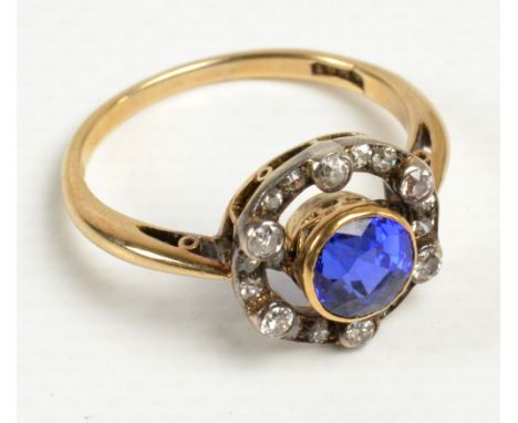 An 18ct yellow gold diamond and sapphire ring, the central violetish blue round brilliant cut sapphire weighing approx 1.20ct